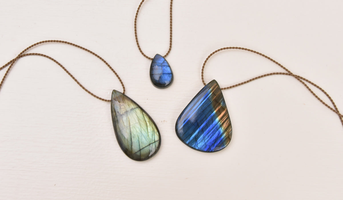 Raw labradorite stone showing the play of color against a dark base. Alt text: "Raw labradorite mineral showing blue and gold labradorescence