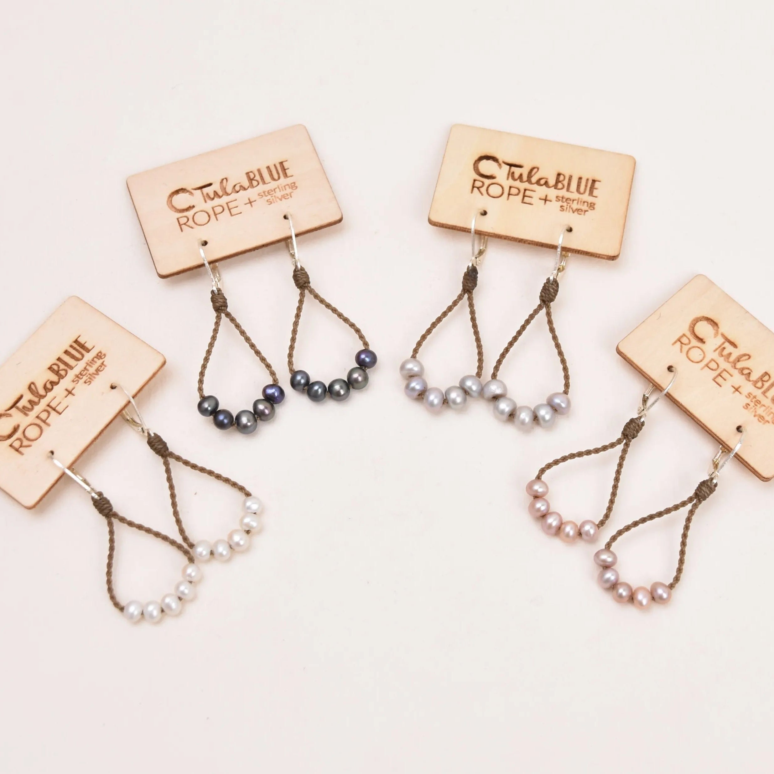 dainty pearl earrings in white, peacock, silver, and blush on a white background