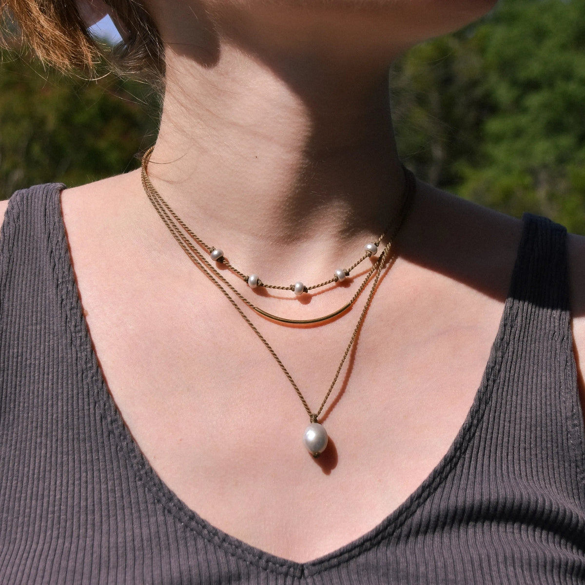 Dripping in Pearls necklace stack in silver on model with trees in background