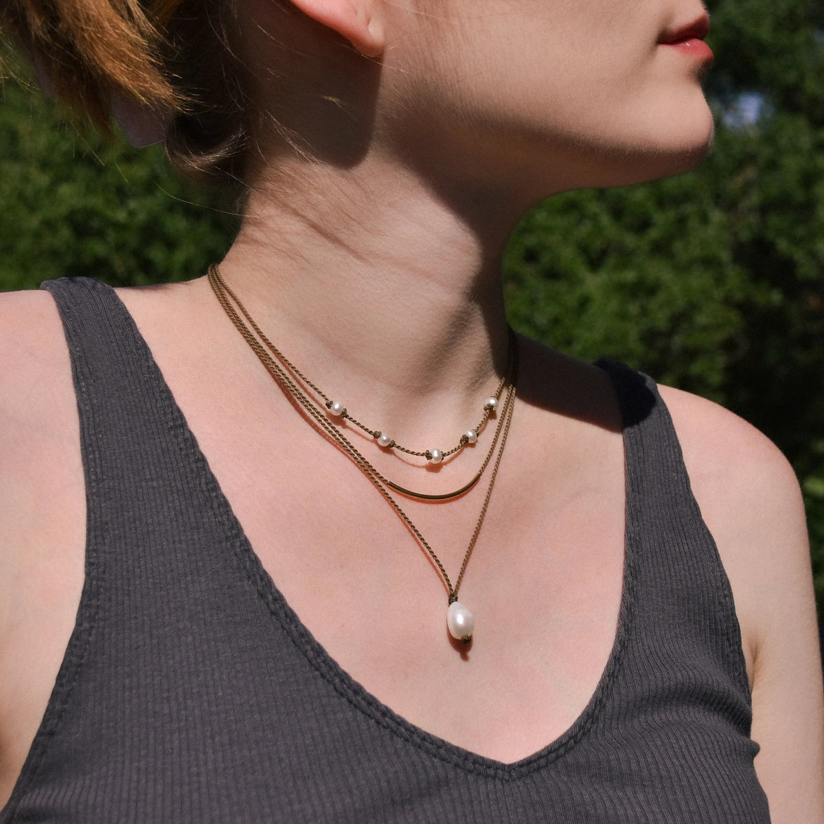 Dripping in Pearls necklace stack in white on model with trees in background