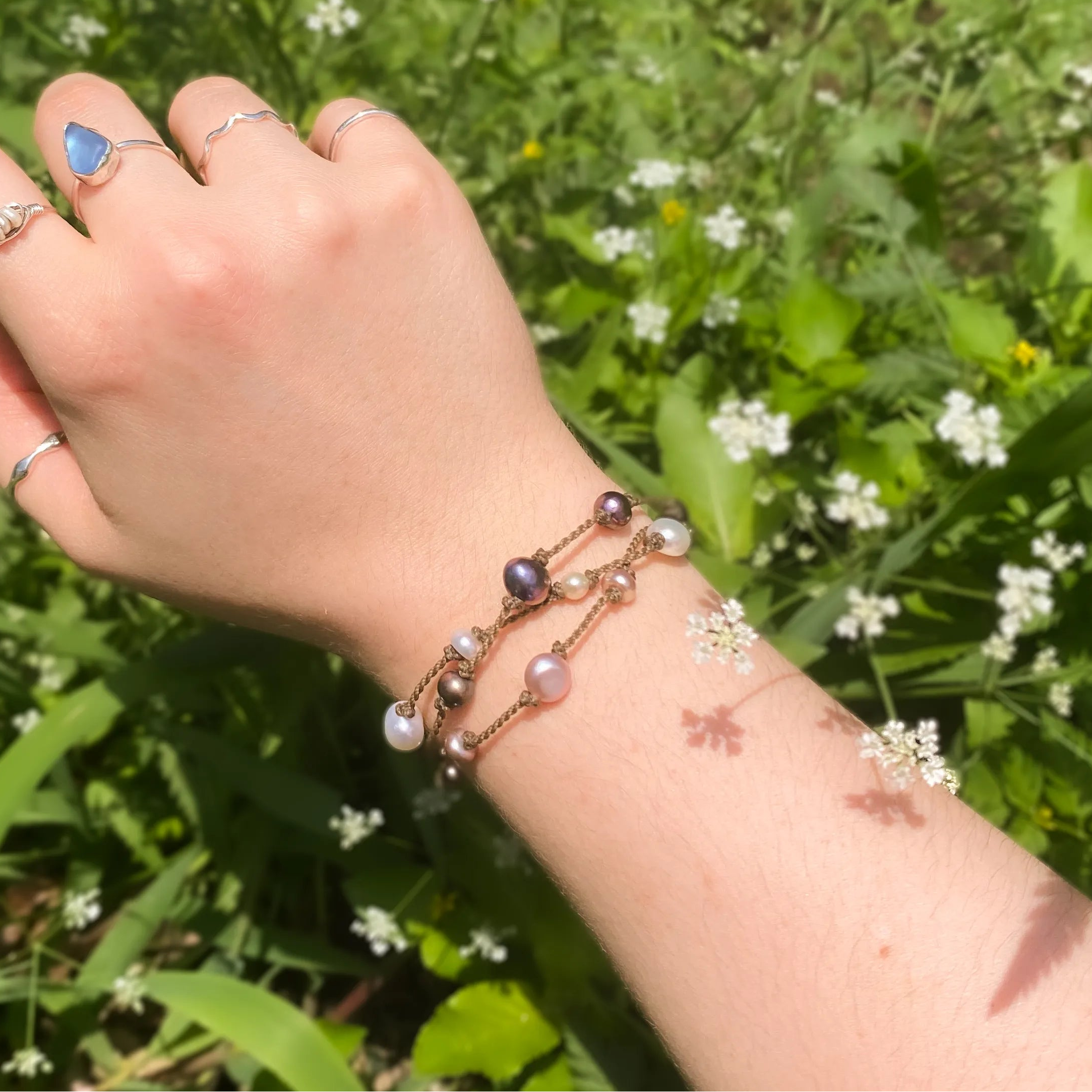 Tula Blue's Journey Bracelet in mixed pearls on model wrist in front of greenery