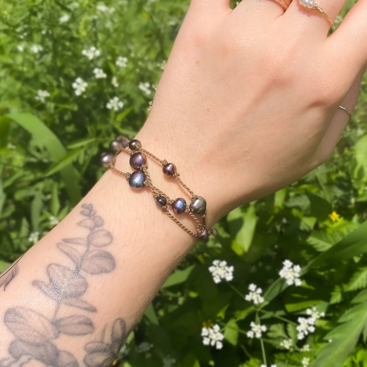 Tula Blue's Journey Bracelet in peacock pearl on model wrist in front of greenery