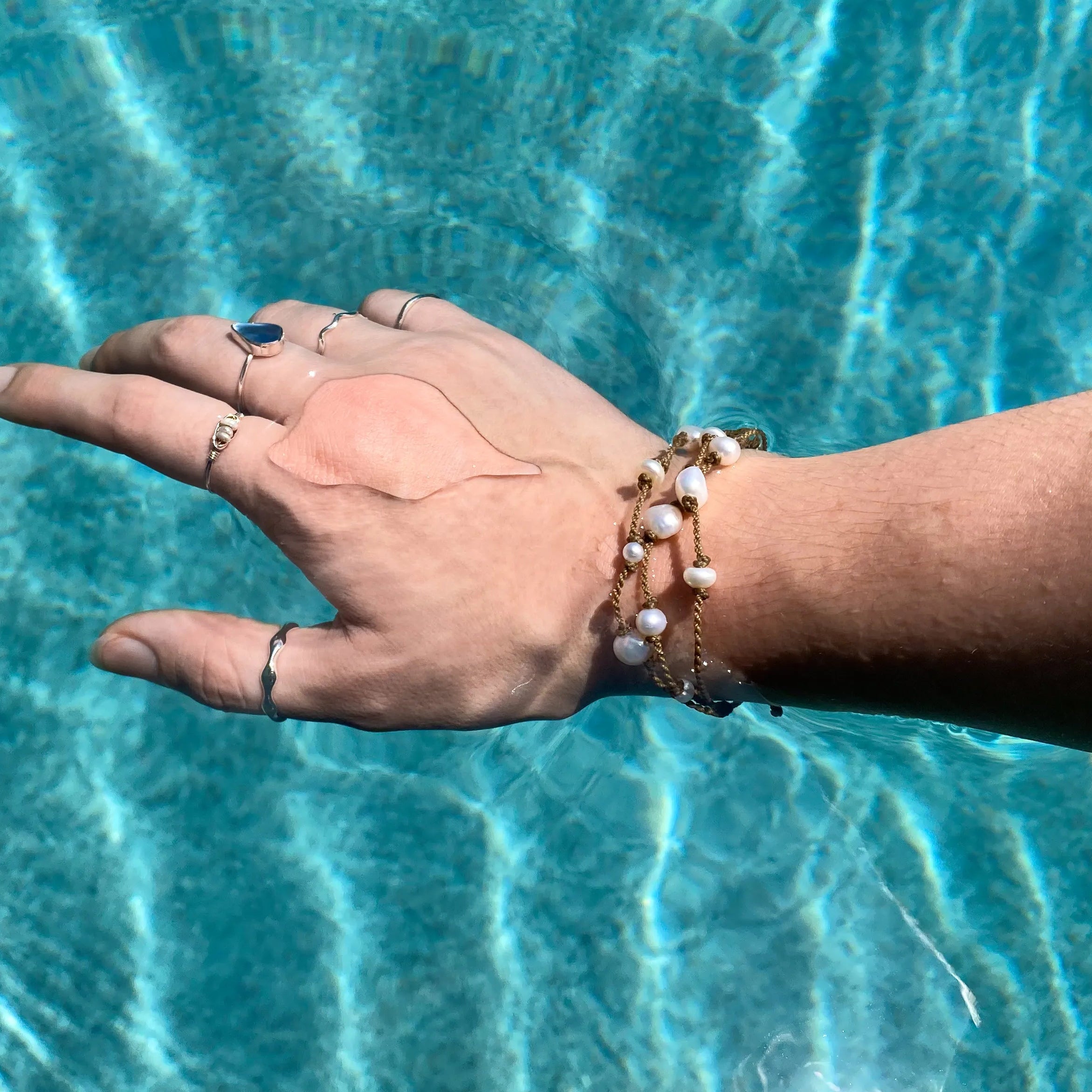 Tula Blue's Journey Bracelet in white pearl on model wrist in water