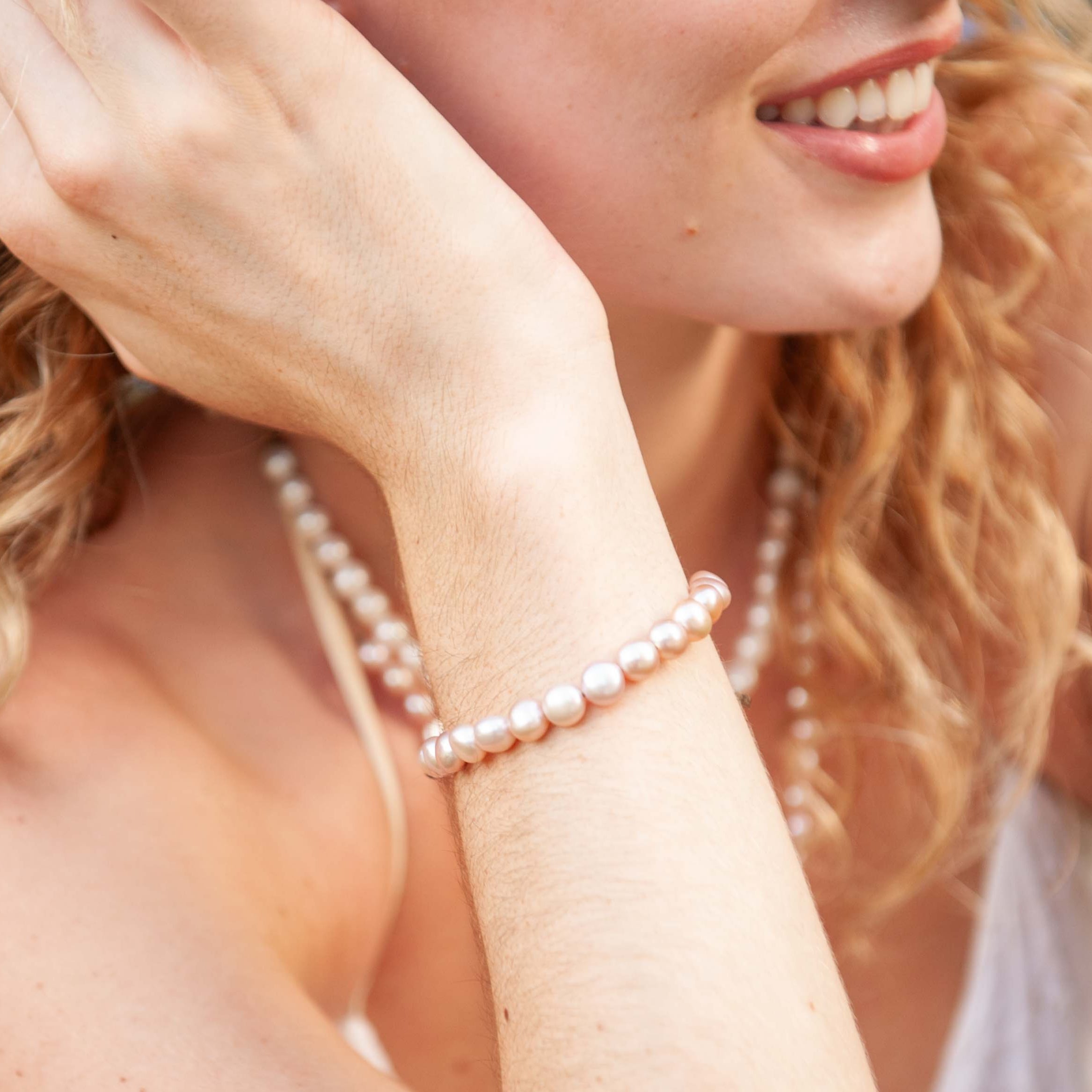 Woman wearing a blush pearl bracelet and necklace outdoors