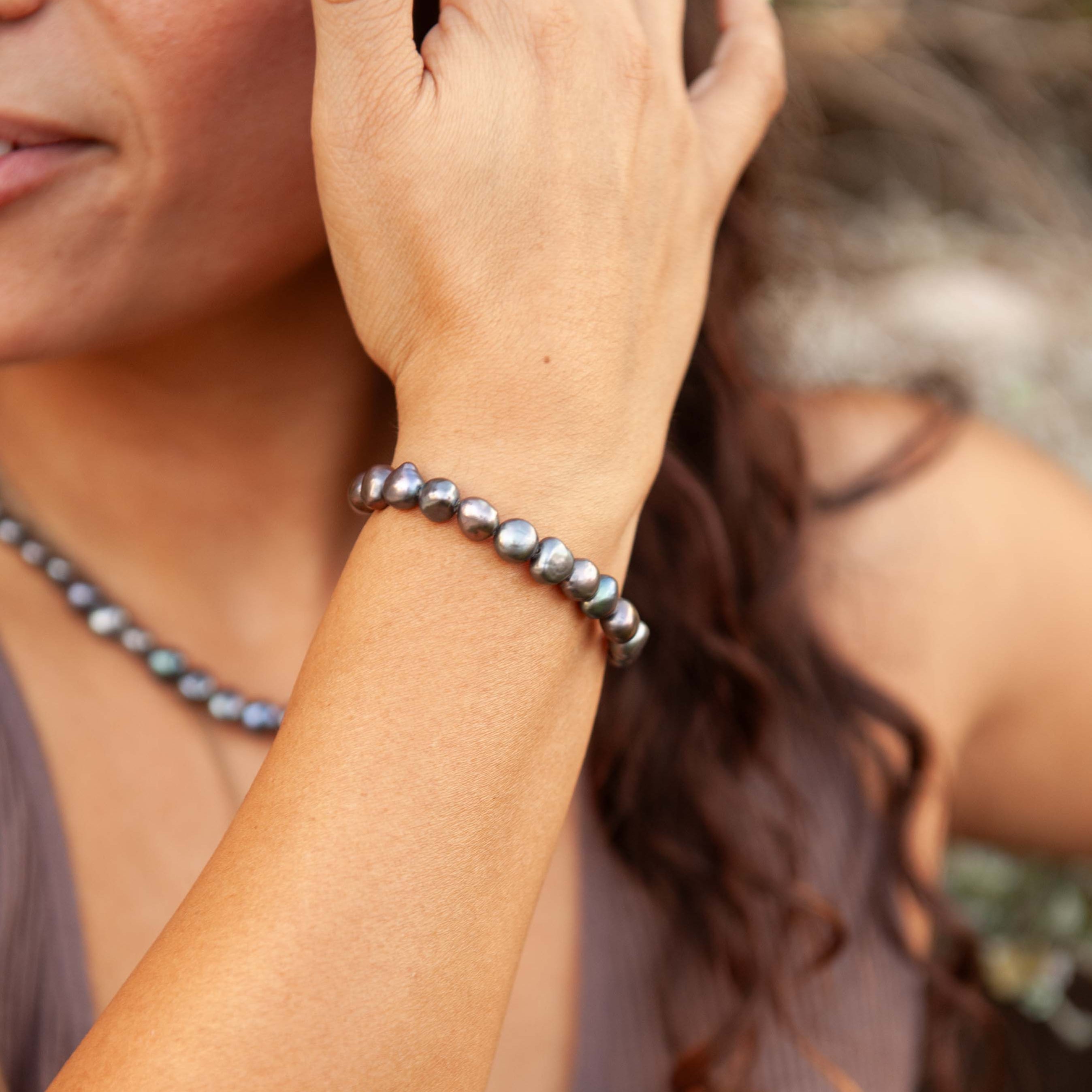 Woman wearing a pearl bracelet with a blurred natural background