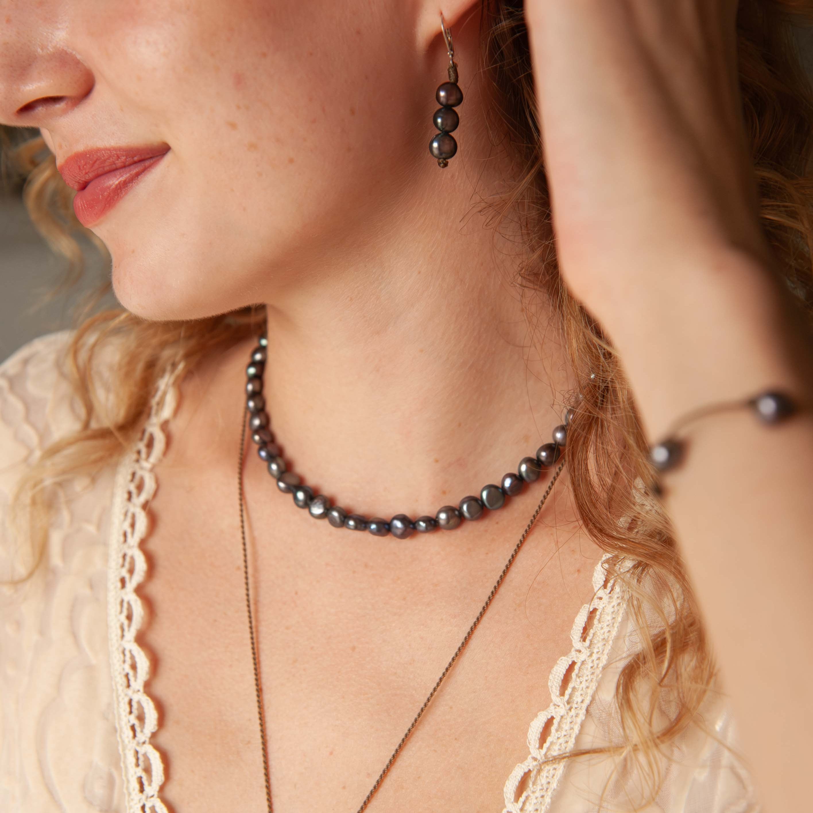 Woman wearing a pearl necklace and earrings with a lace top.