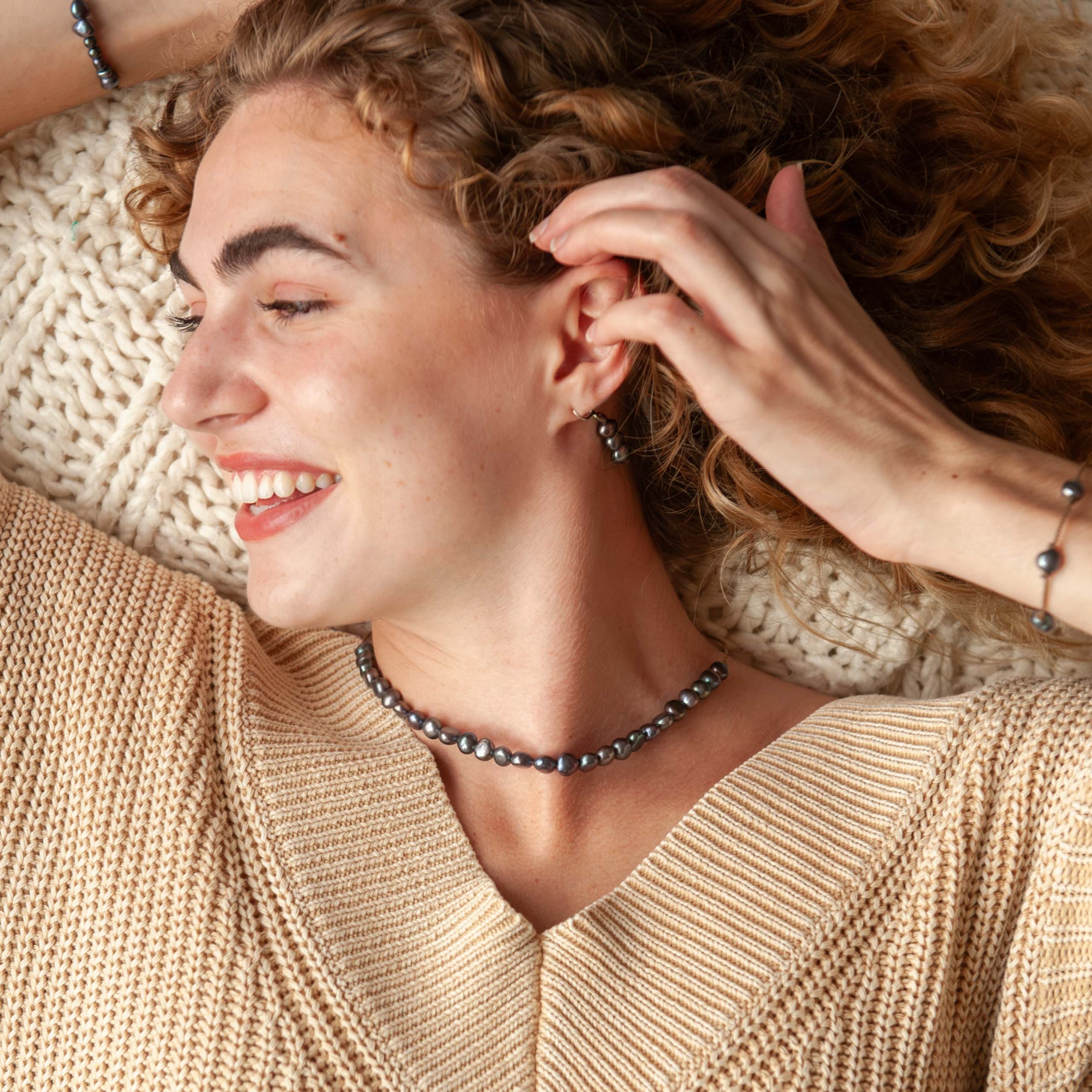 Person wearing a beige sweater with a pearl necklace.