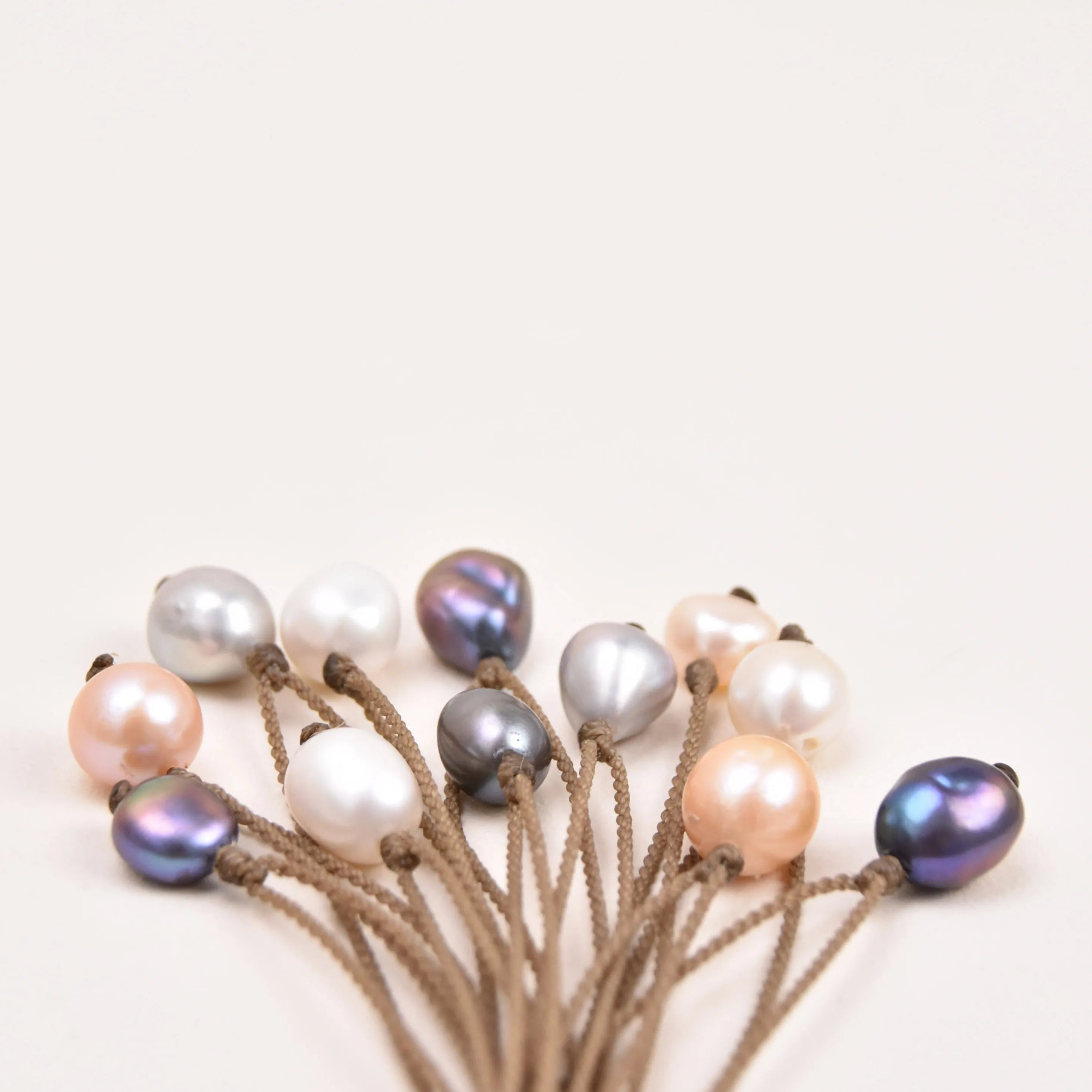 Pearl Drop Necklace in White, Peach, Peacock and Silver clumped on a white background