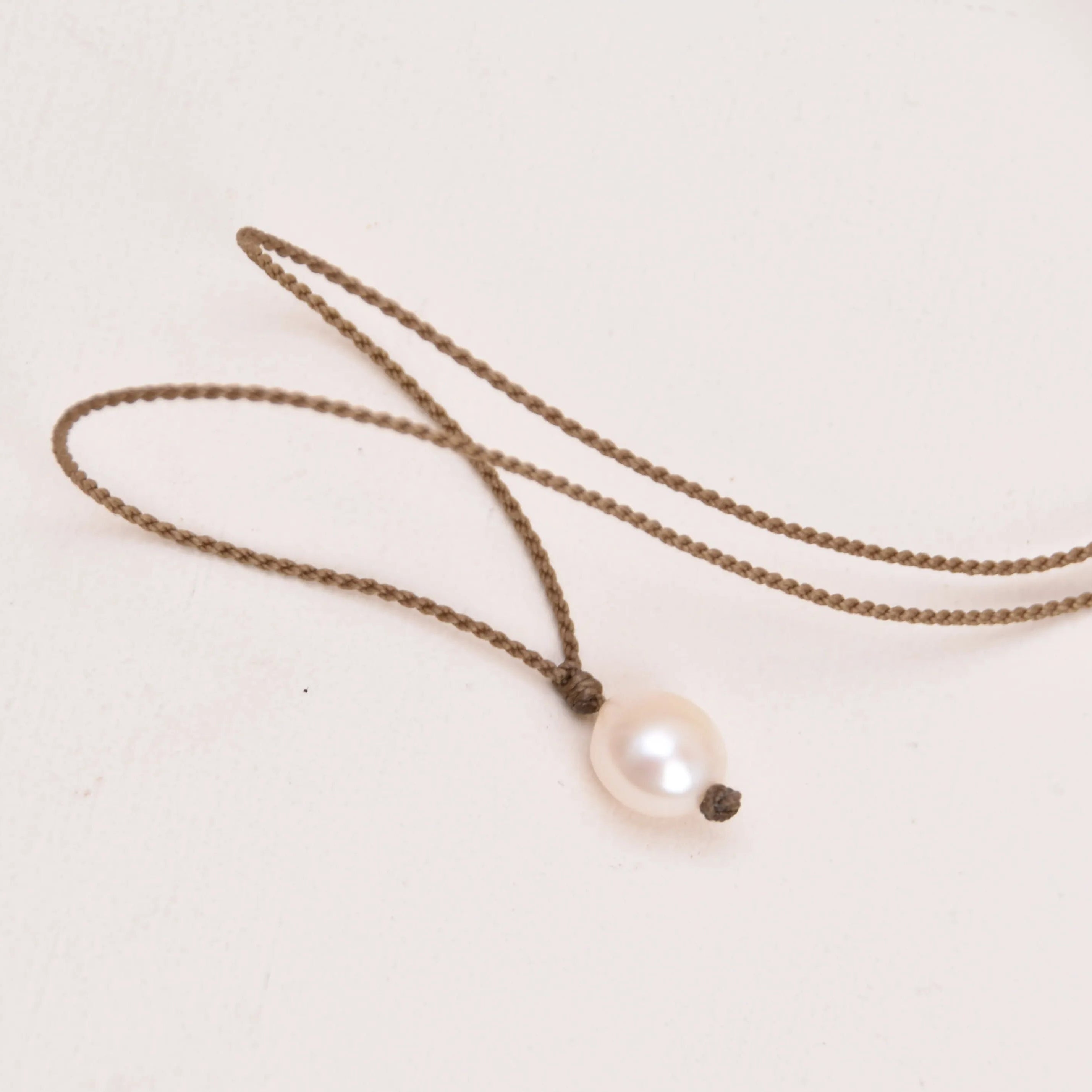 Pearl Drop Necklace in peach laying on a white background