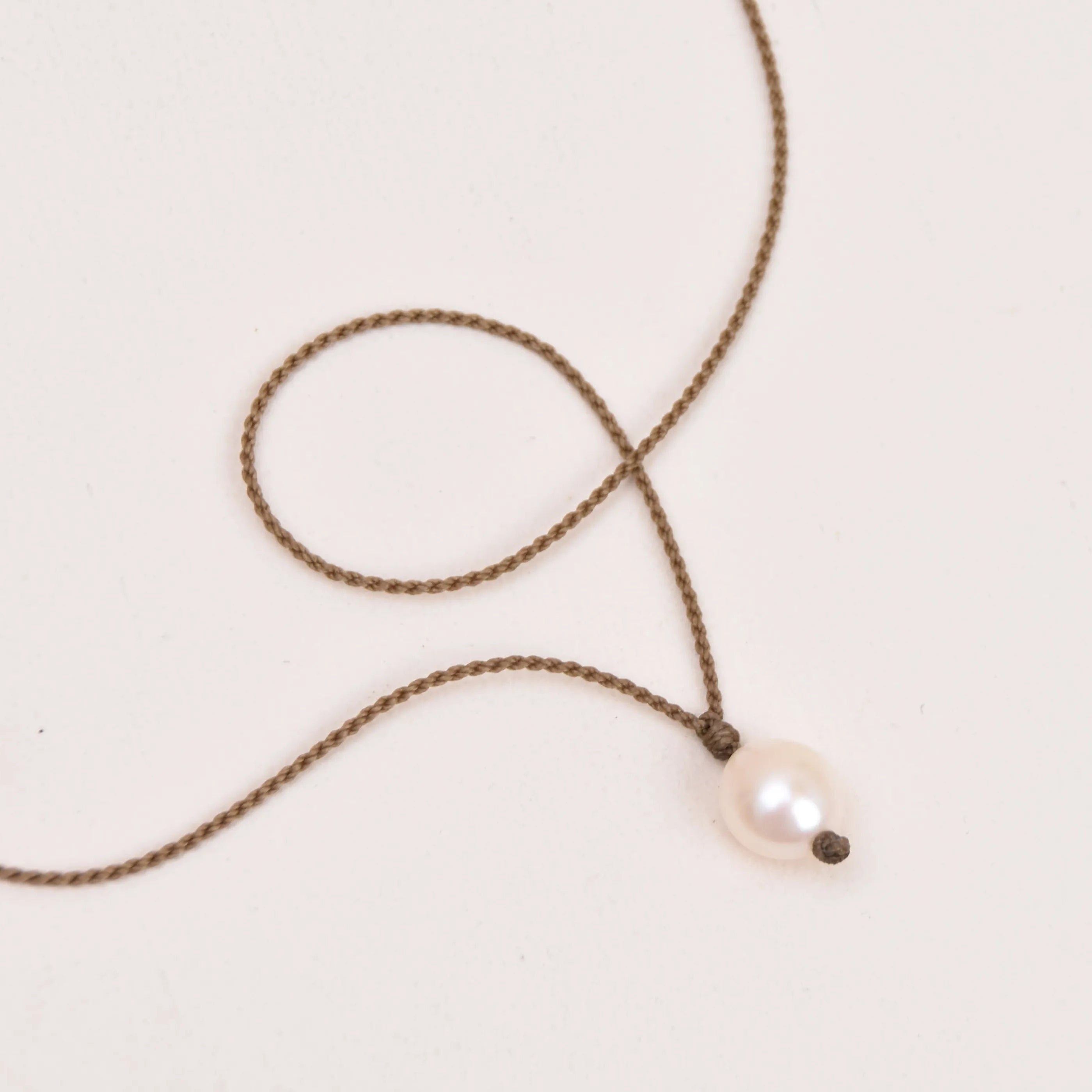 Pearl Drop Necklace in white laying on white background