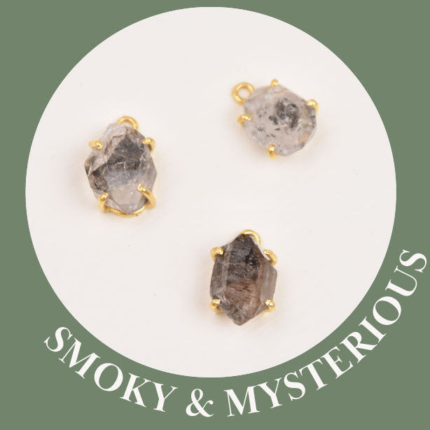 Close-up of three smoky Herkimer Diamond pendants with a bezel-set, double-terminated crystals, showing the natural variation in darker stone tones.