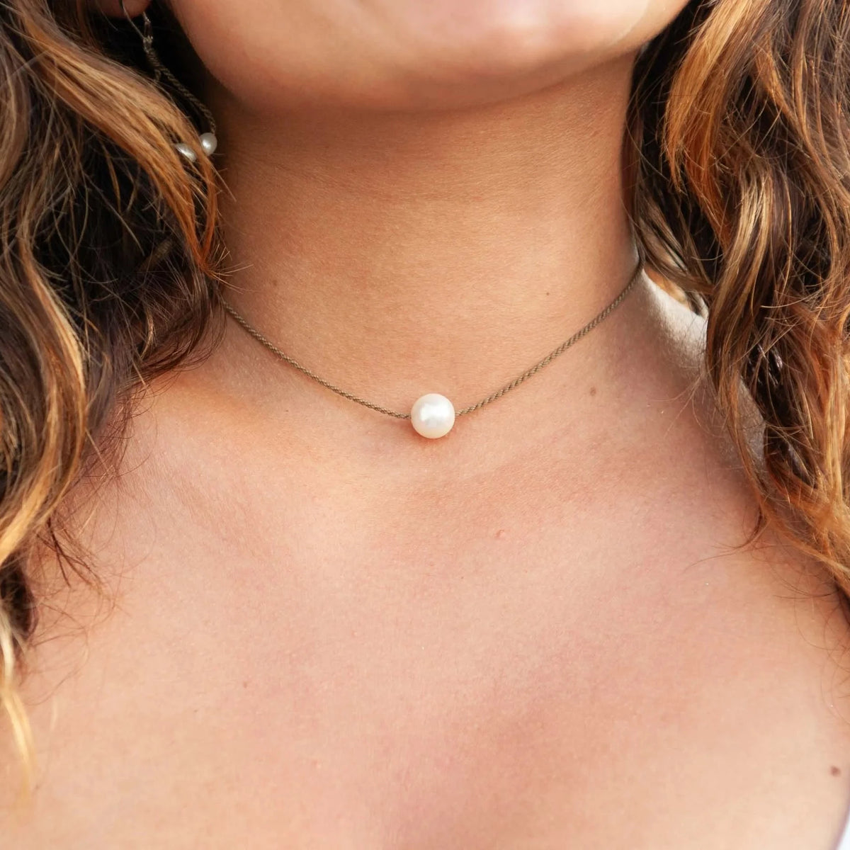 Close-up of the Classic Pearl Necklace worn at the collarbone, one white Edison freshwater pearl on hand-spun rope