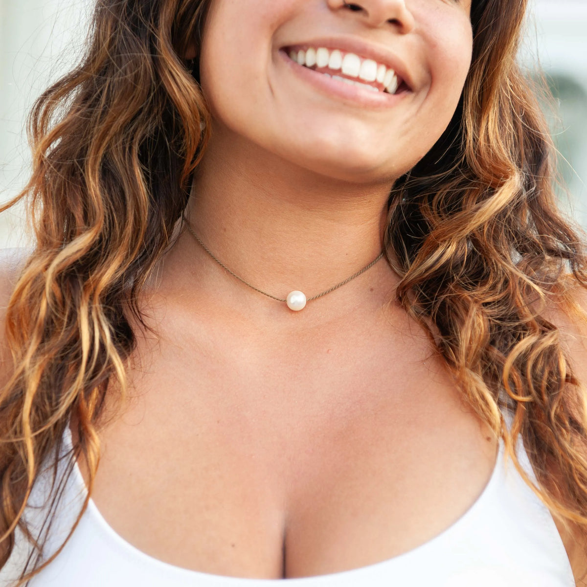 Woman smiling in a white top, wearing the Classic Pearl Necklace with one white Edison freshwater pearl on hand-spun rope