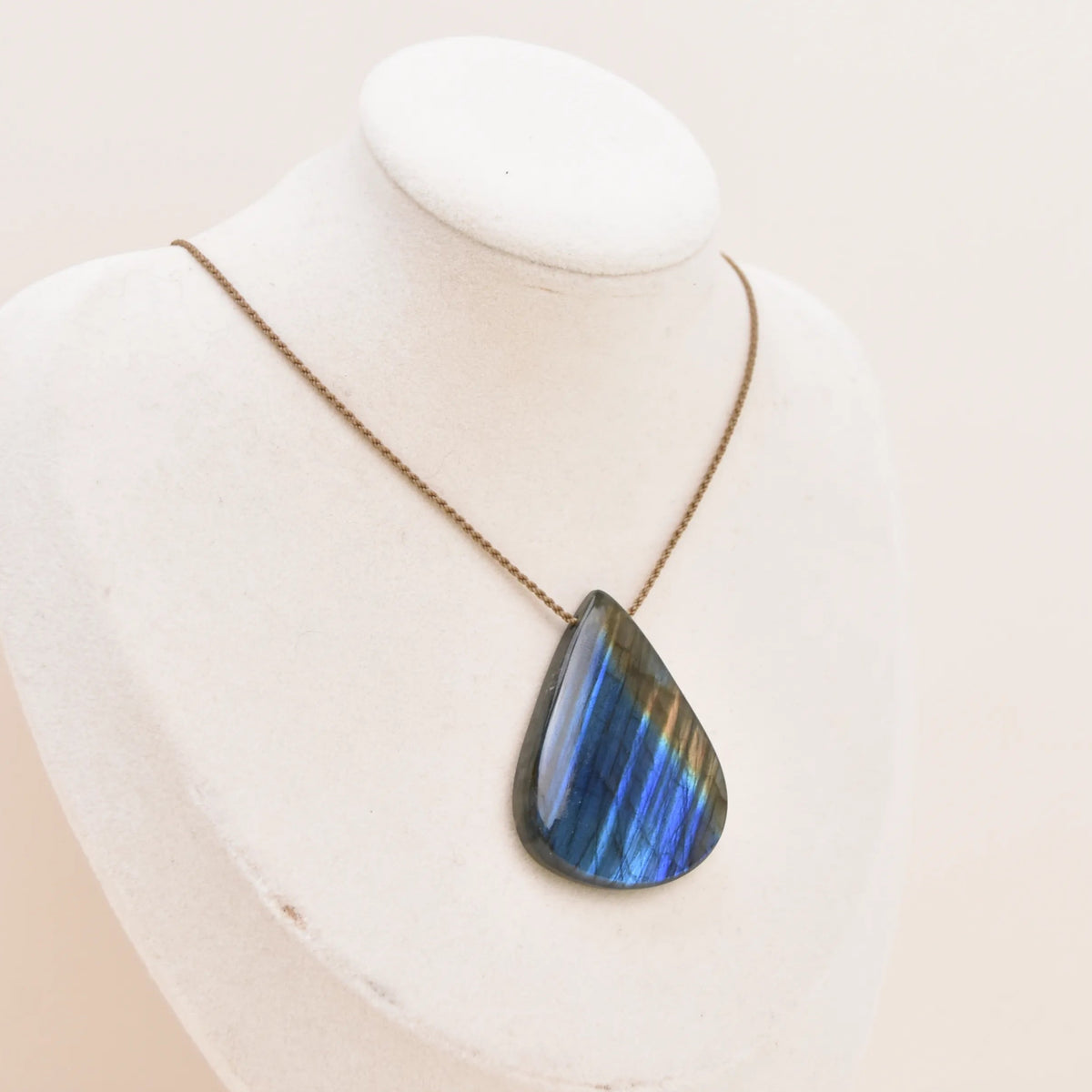 Labradorite Gemstone Pendant, large blue teardrop with gold edge on hand-spun rope on a white bust