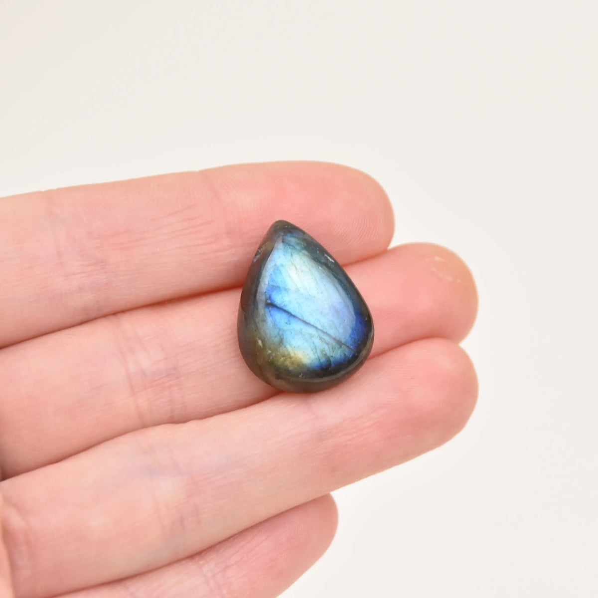 Labradorite Gemstone Pendant stone with blue flash held between fingers to show size