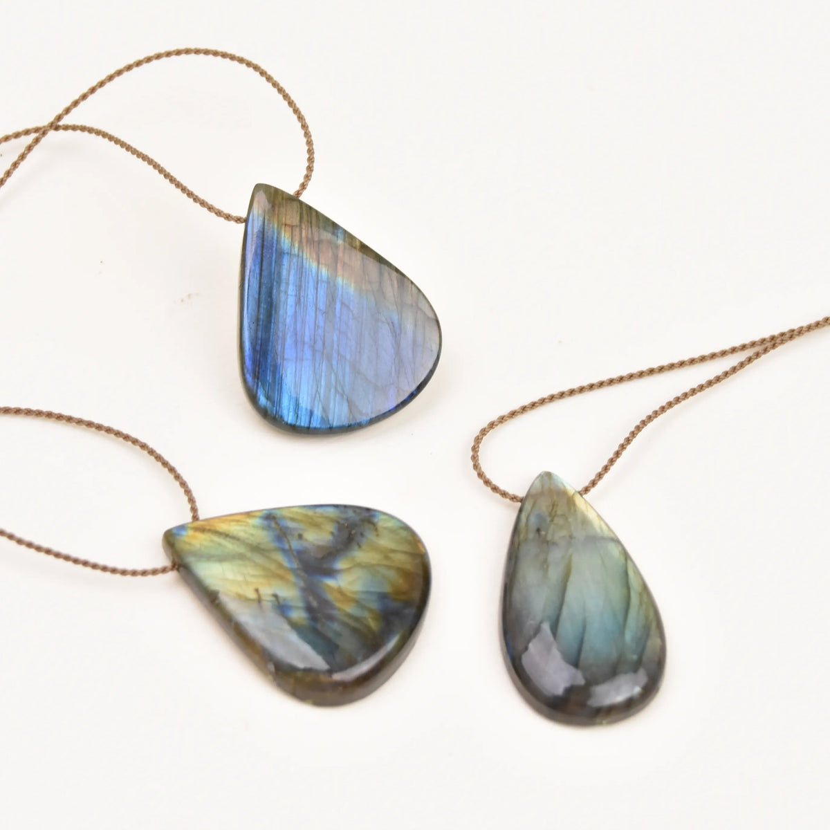 Labradorite Gemstone Pendant trio with blue, gold and green flash on hand-spun rope, flat lay