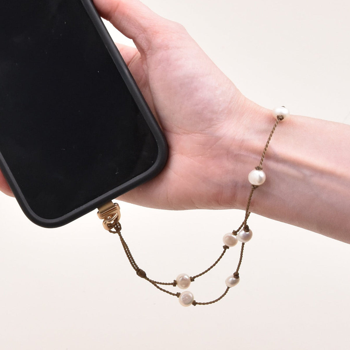 Woman with a pearl phone wristlet on her wrist