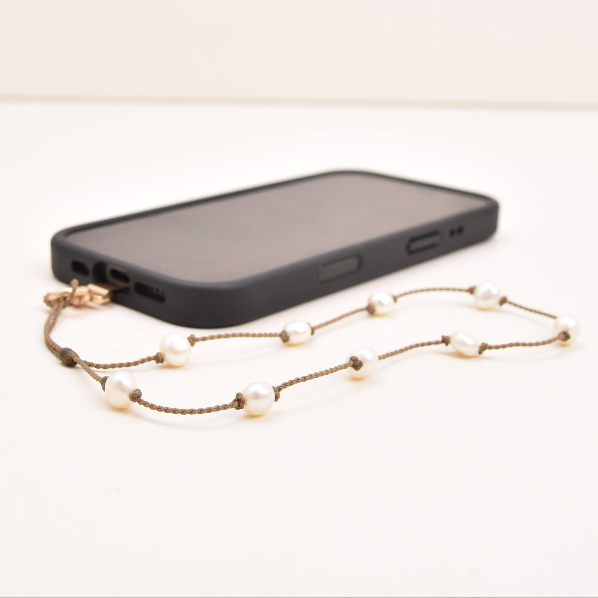 White freshwater pearl phone wristlet on hand-spun rope with phone attached