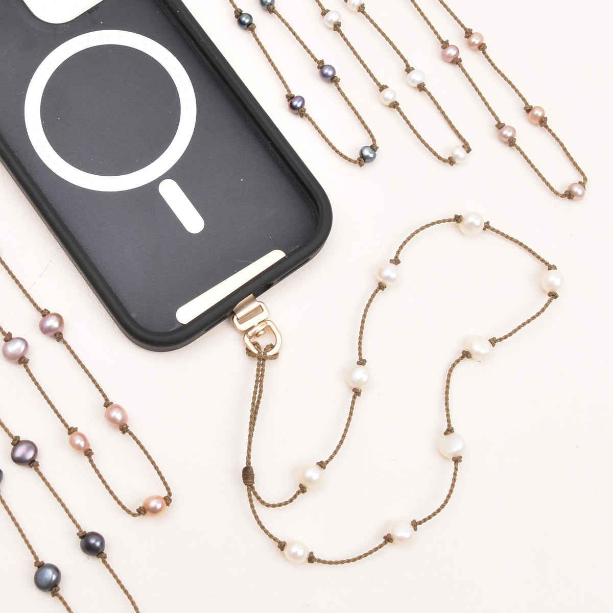Peacock, blush, and white freshwater pearl phone strap on hand-spun rope with phone attached