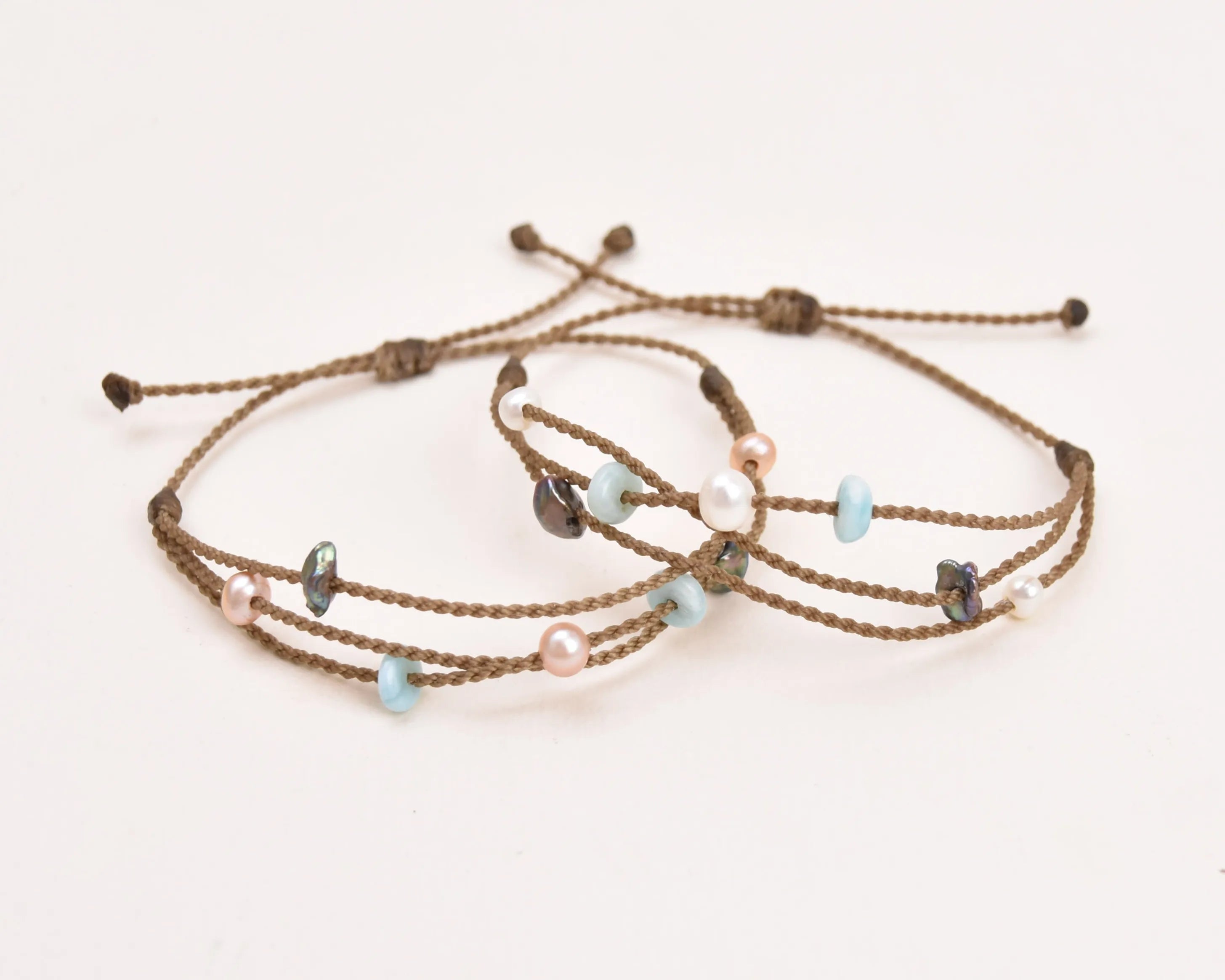 Seven Seas X PADI Riptide Bracelets with blush and white pearls stacked on top of each other on white background