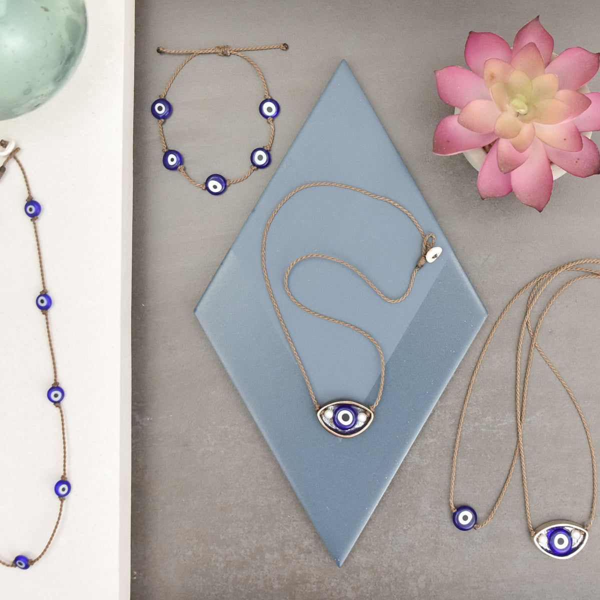 Evil eye jewelry flat lay with the Evil Eye Bracelet and evil eye necklaces on hand-spun rope