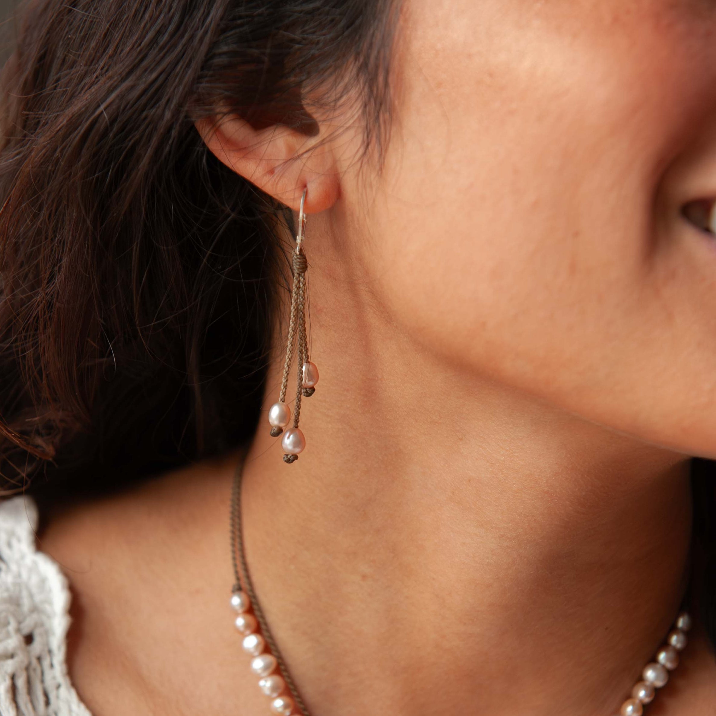 Close-up of a woman wearing a pearl necklace and earrings.