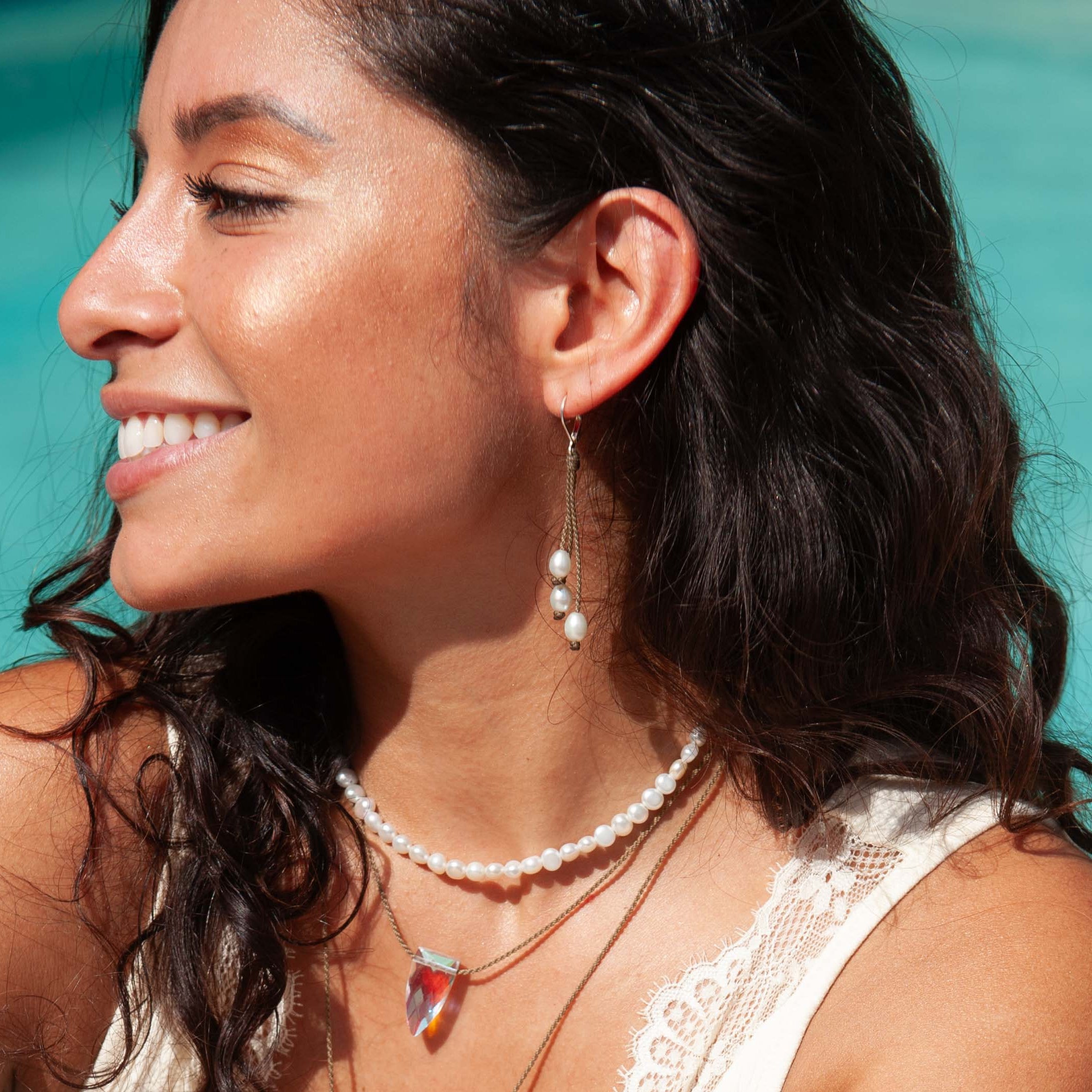 Woman in a white dress with jewelry by a pool