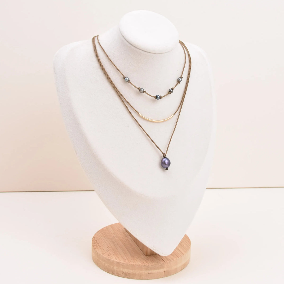Dripping in Pearls necklace stack in peacock on bust with white background
