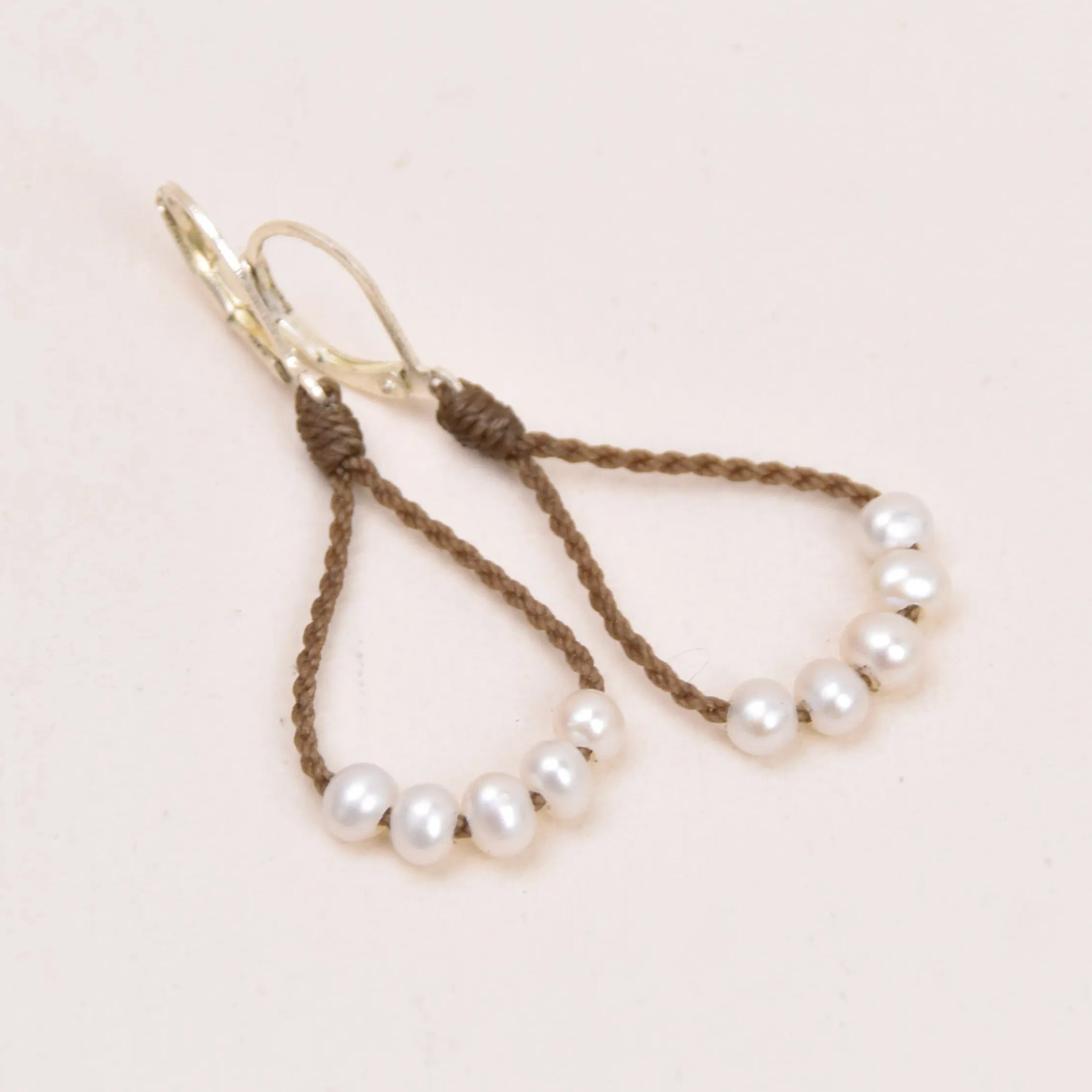 dainty pearl earrings in white on white background