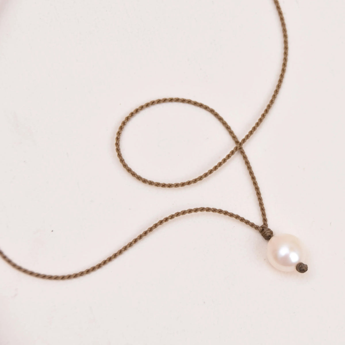 pearl drop necklace in white on white background