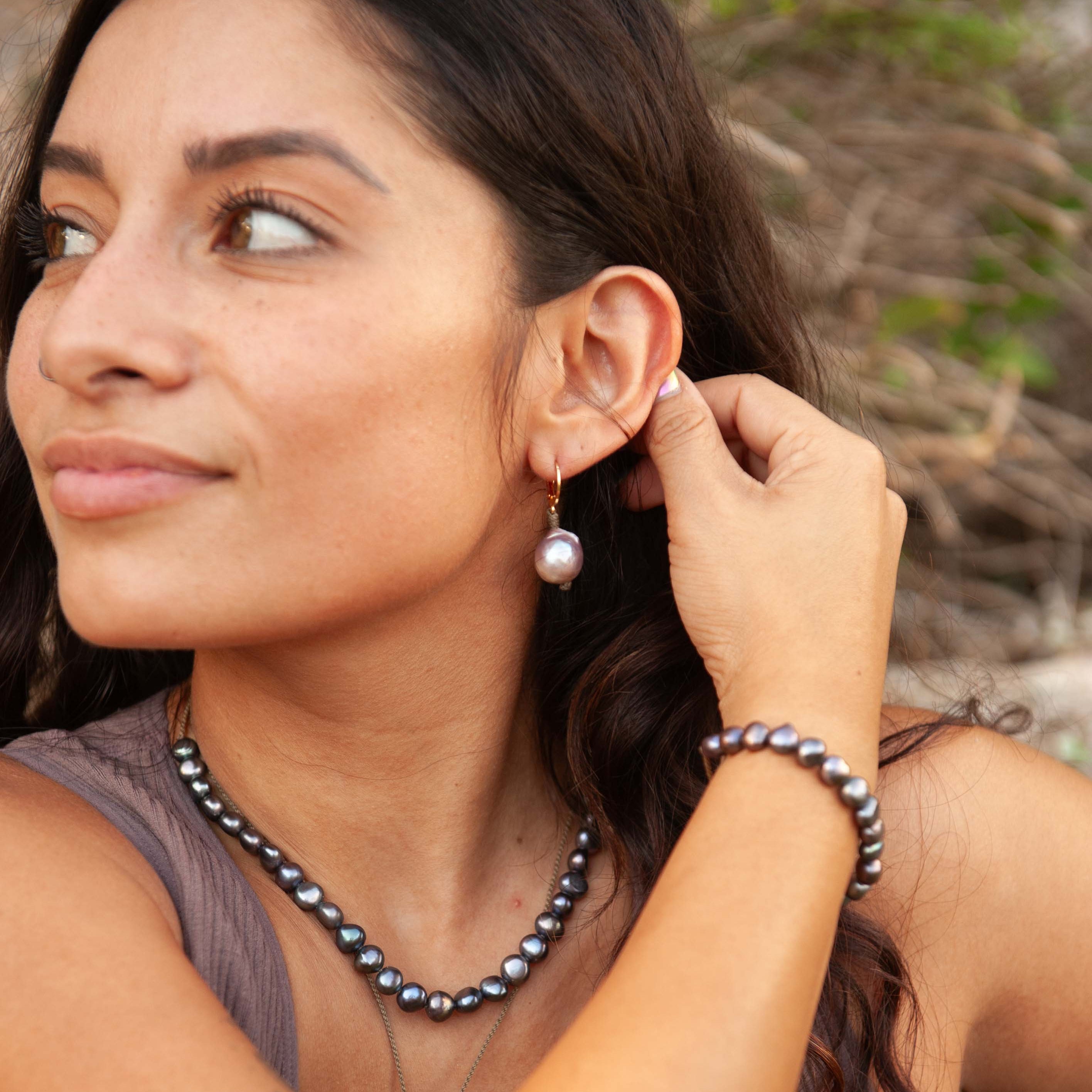 Woman wearing Tula Blue pearl earring and necklaces outdoors