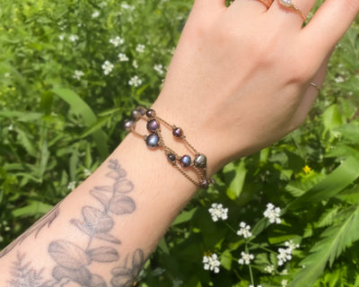 Tula Blue's Journey Bracelet in peacock pearl on model wrist in front of greenery