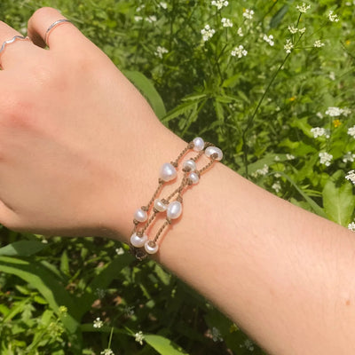 Tula Blue's Journey Bracelet in white pearl on model wrist in front of greenery