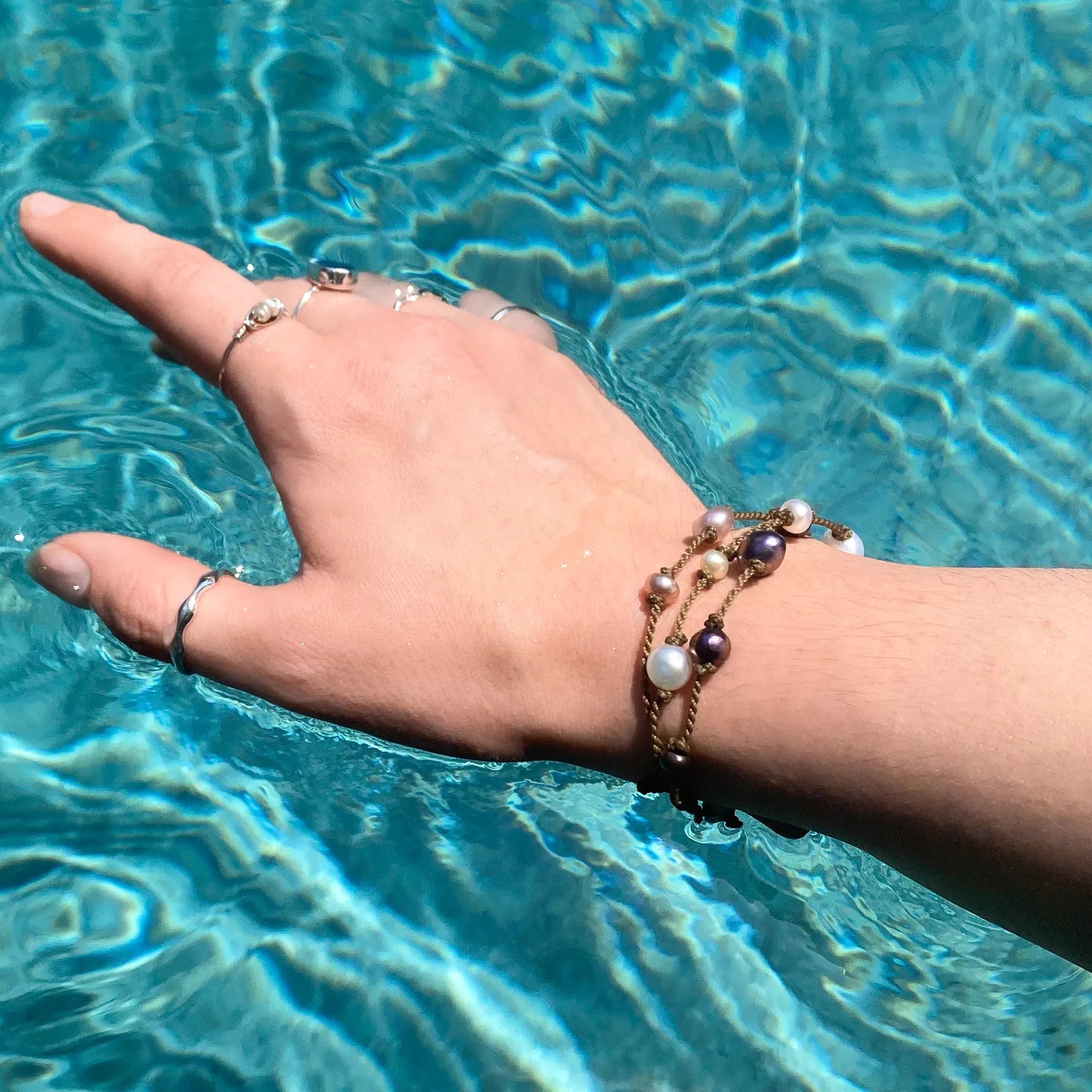Tula Blue's Journey Bracelet in mixed pearl on model wrist in water closeup