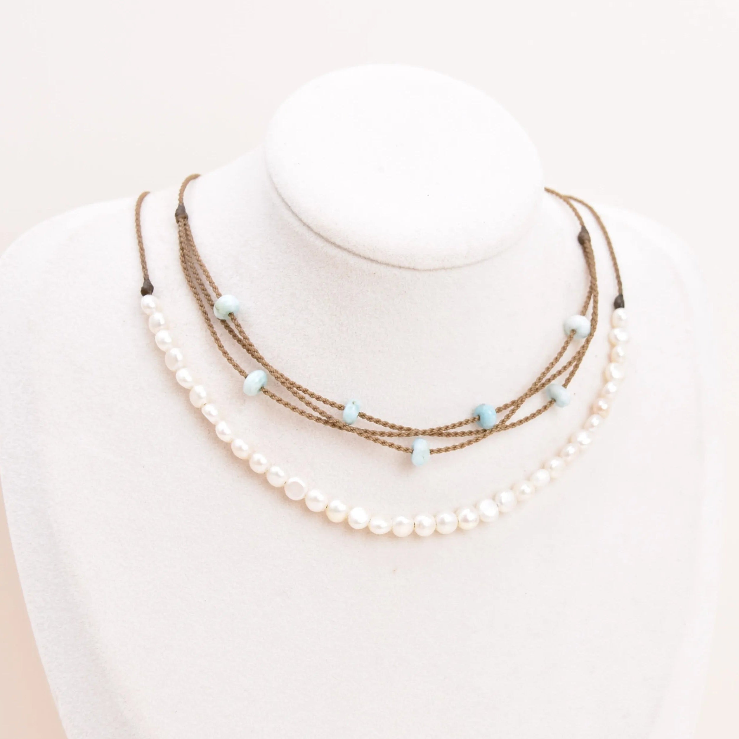 White Pearl Crown Necklace and Larimar Riptide necklace on white bust