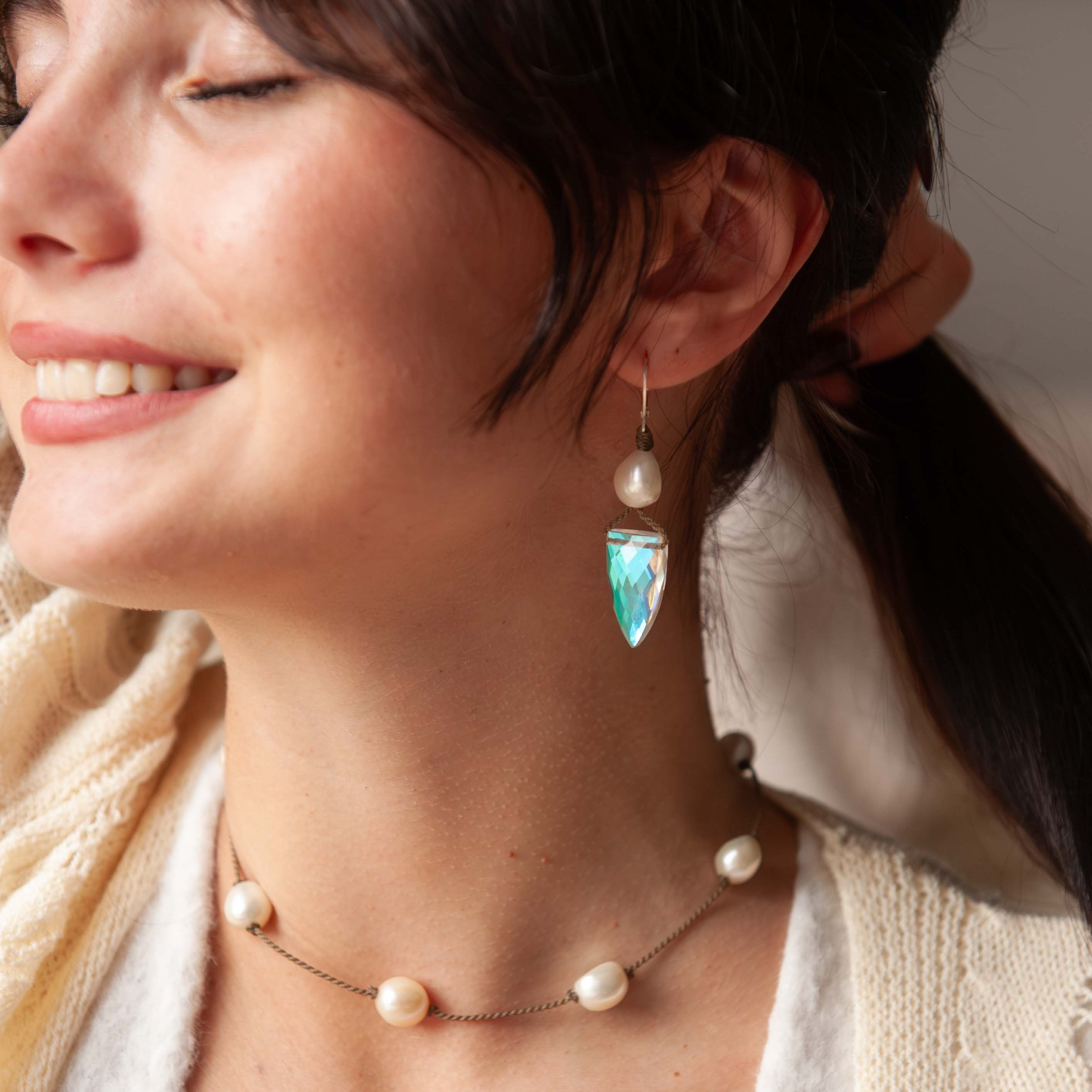 Woman wearing a pearl necklace and earrings with a blurred background