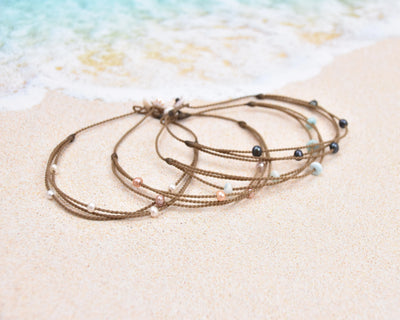 Tula Blue's waterproof Riptide anklet options in white pearls, blush pearls, larimar stones and peacock pearls. 