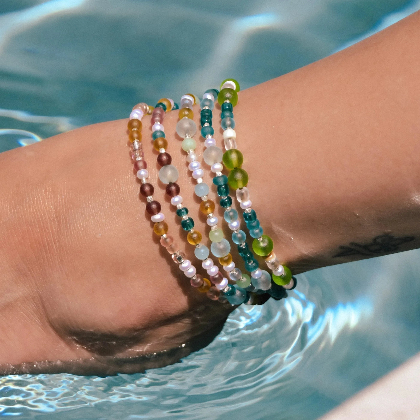 All sea glass anklets on one model's ankle in the pool water