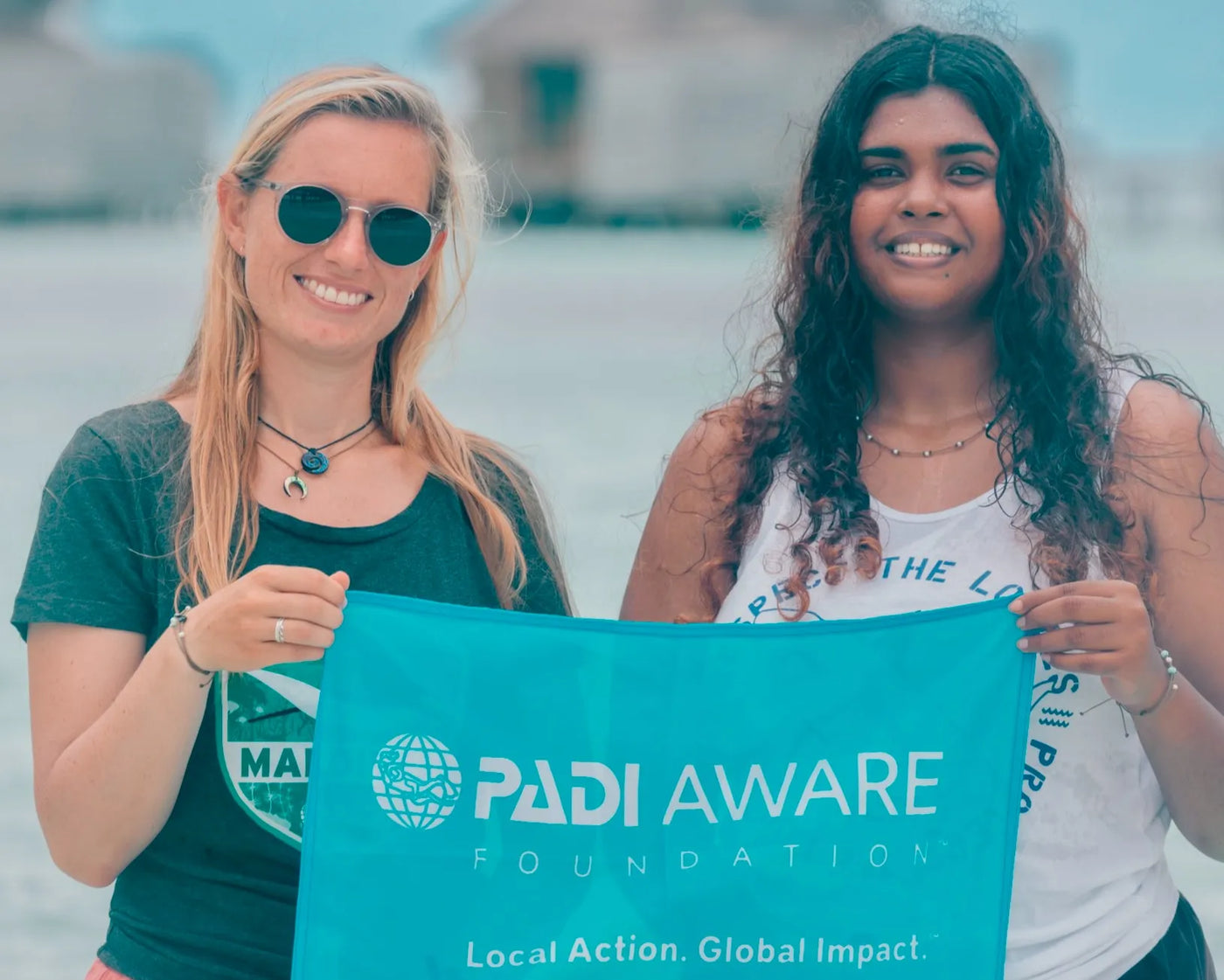 Seven Seas bracelet on PADI divers on the beach holding PADI Aware Banner
