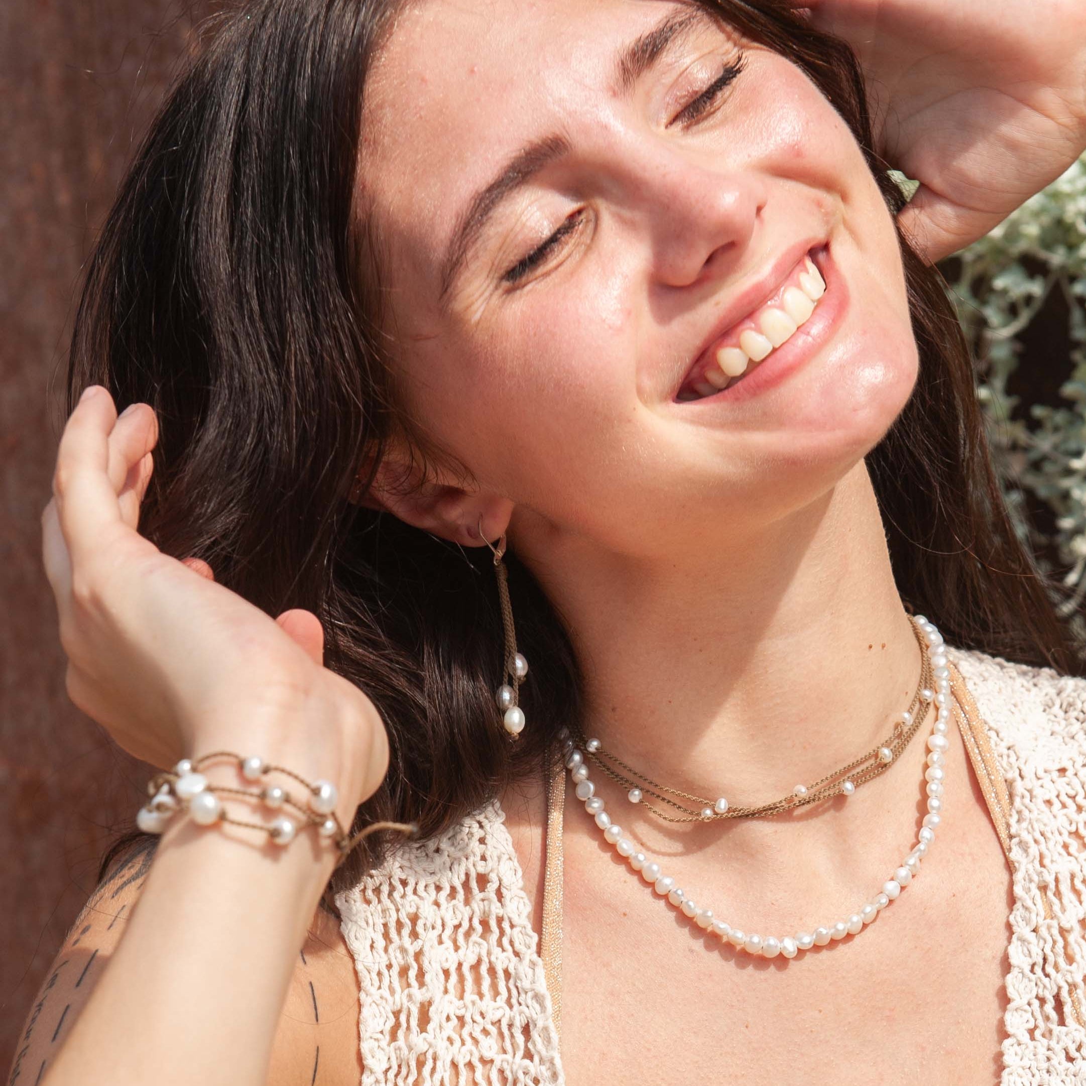 Woman wearing a beige crochet top with Tula Blue jewelry and earrings.