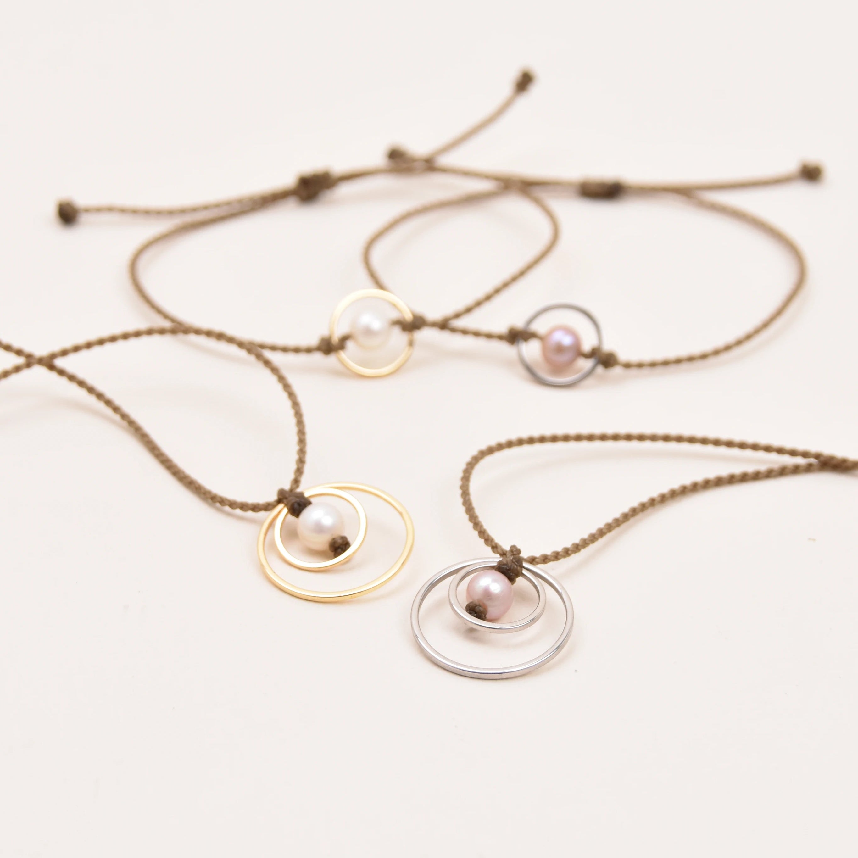 rope necklaces with minimalist concentric circle pendants and pearls, shown on a plain white background.