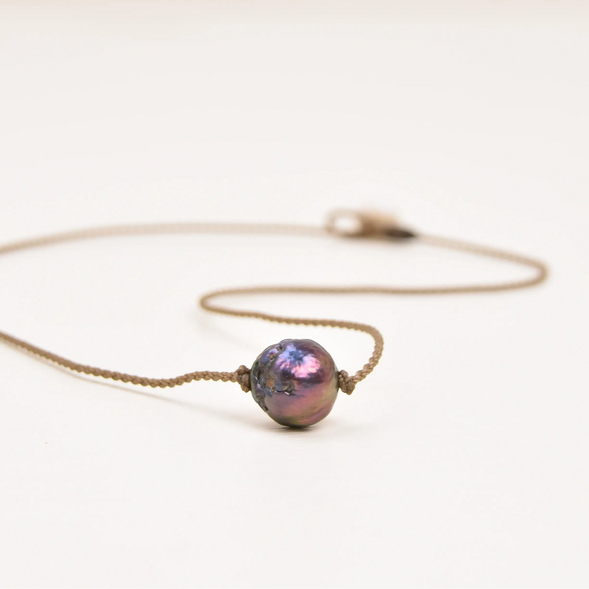 Classic Pearl Necklace laid flat, one peacock Edison freshwater pearl knotted on hand-spun waterproof rope