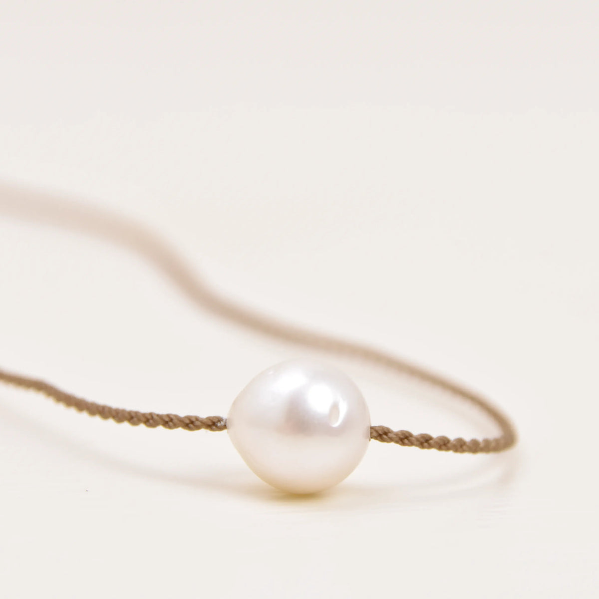 Close-up of a white Edison freshwater pearl on the Classic Pearl Necklace's hand-spun waterproof rope