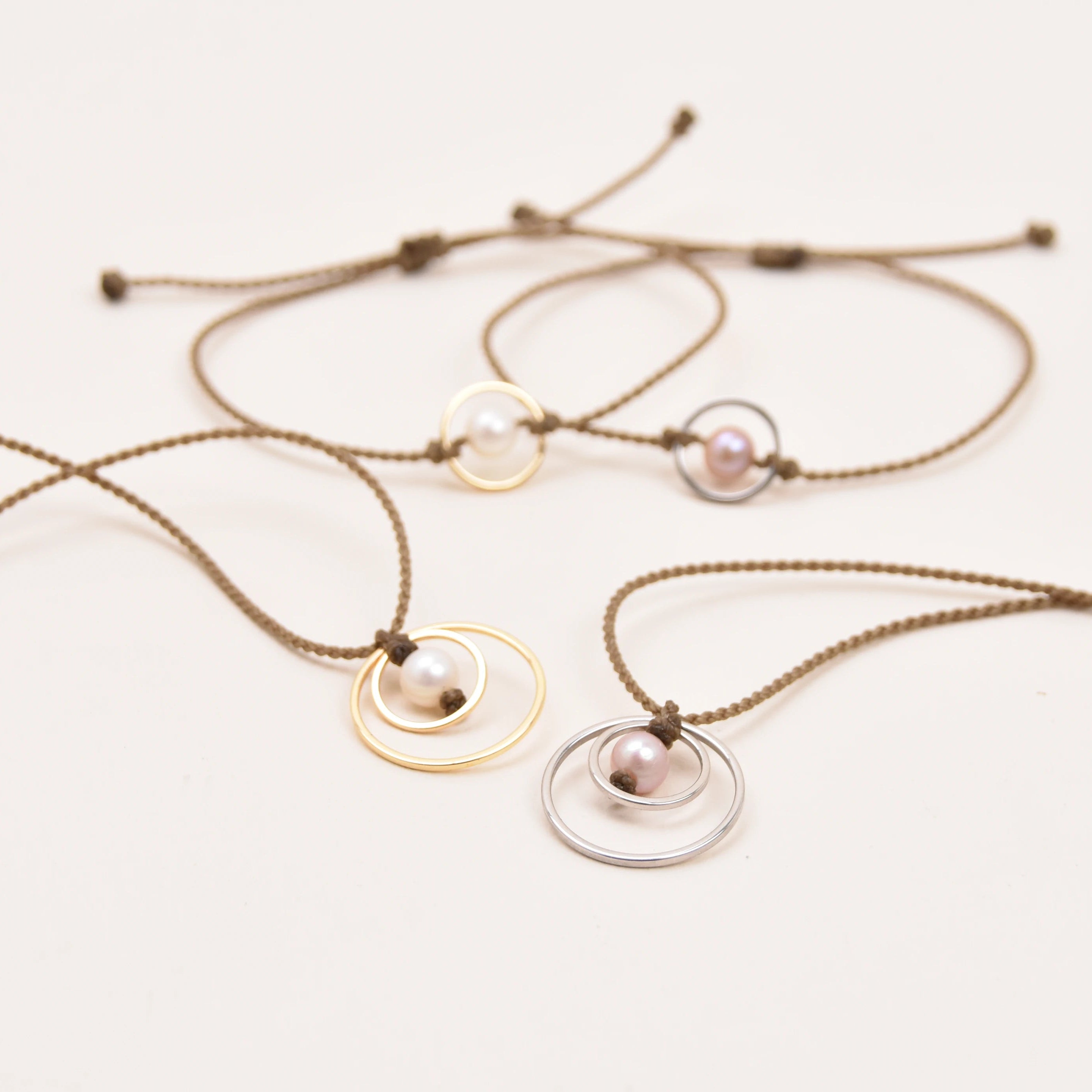 rope necklaces with minimalist concentric circle pendants and pearls, shown on a plain white background.