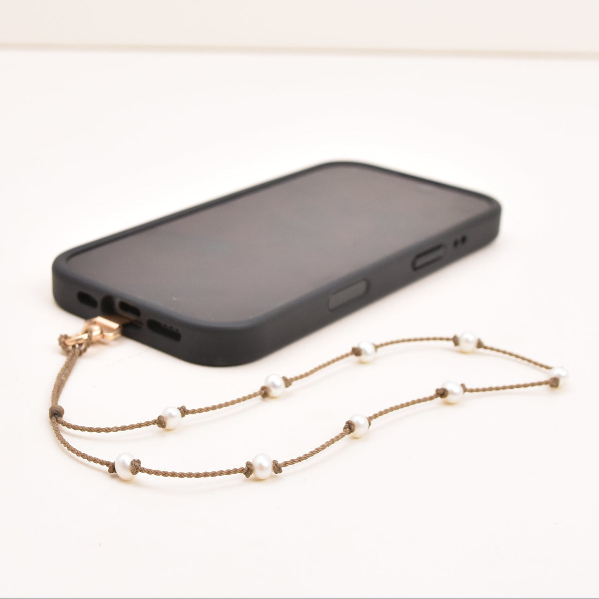 White freshwater pearl phone wristlet on hand-spun rope with phone attached