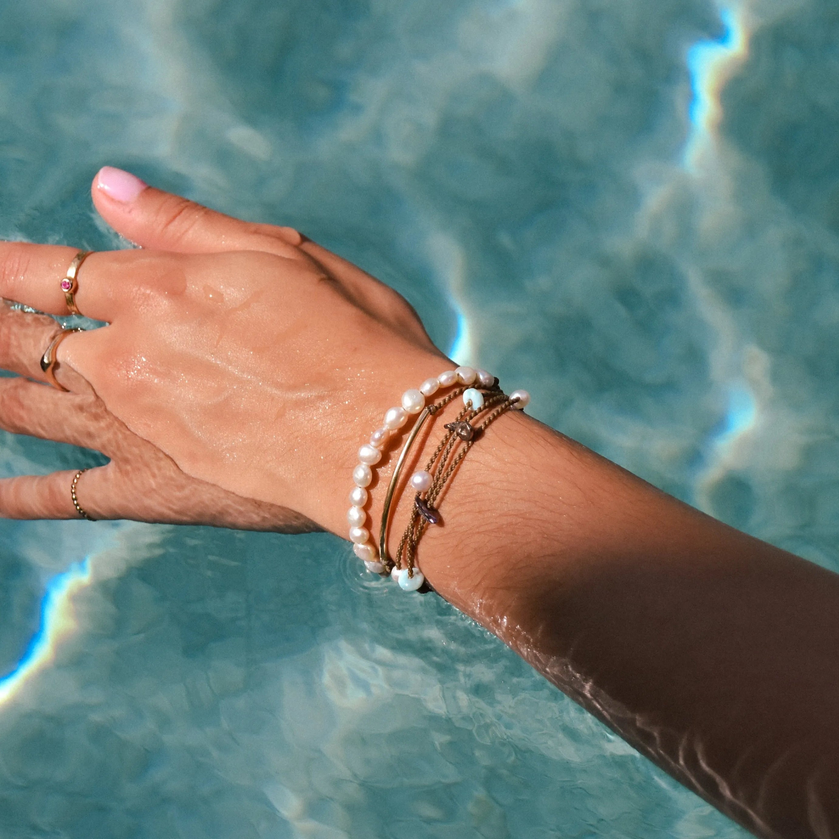 Seven Seas bracelet stack in white on model over pool water