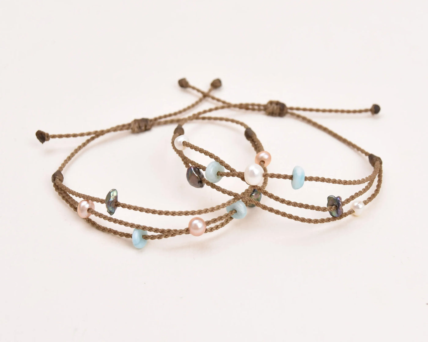 Seven Seas X PADI Riptide Bracelets with blush and white pearls stacked on top of each other on white background