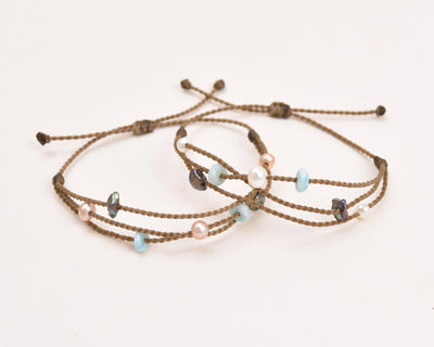 Seven Seas X PADI Riptide Bracelets with blush and white pearls stacked on top of each other on white background