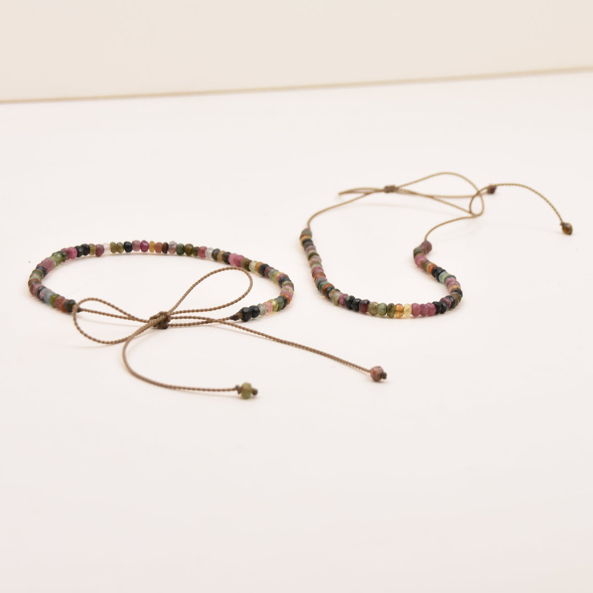 Two adjustable necklaces with small watermelon tourmaline stones, displayed on a plain white surface.