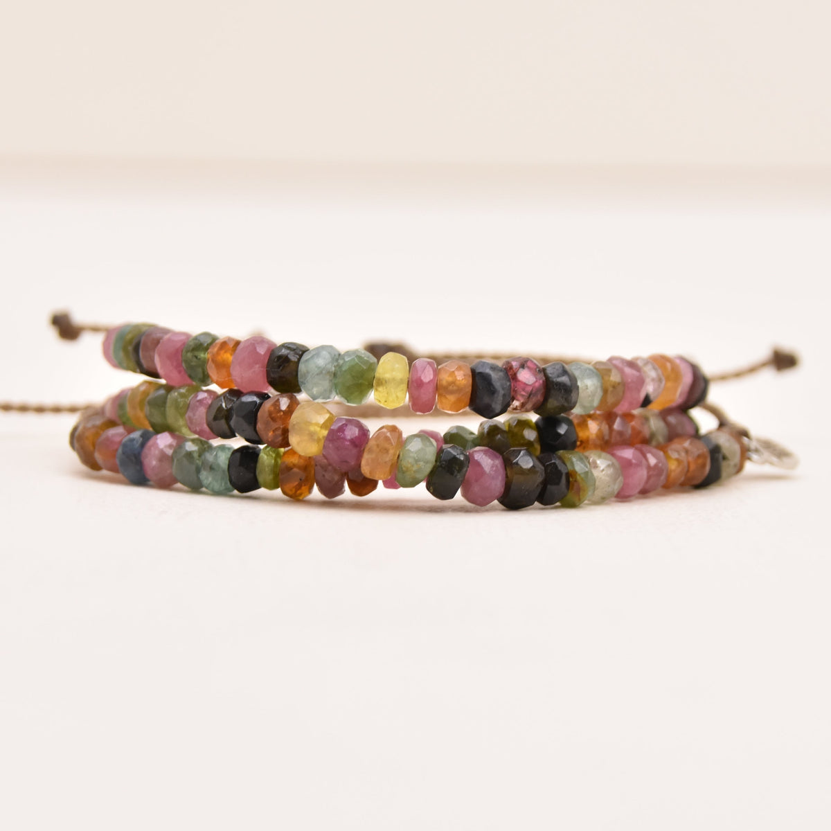 A pair of adjustable rope bracelets decorated with small, faceted multicolor watermelon tourmaline stones, displayed on a clean white background.